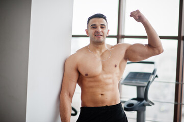 Muscular arab man in modern gym. Fitness arabian men with naked torso show his biceps.