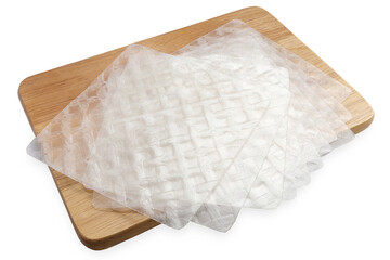 Vietnamese dry rice paper. stack of dried rice paper sheets on wooden cutting board on a white background with clipping path. top view