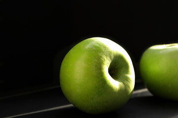 Close up of green apples. Fresh ripe green apple with water drops on a dark background in the sunlight.