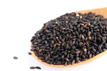 black organic sesame seeds in wooden spoon on a white background.