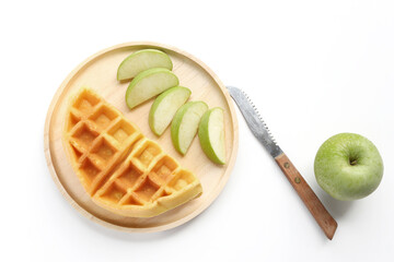 Belgian waffles with green apple on wooden plate for breakfast. Delicious homemade pastry, top view.