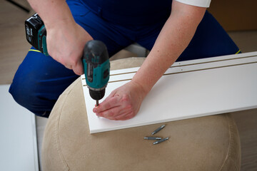 Handyman in a uniform collects furniture. Screw tightening with a screwdriver