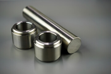 Turned milled metal parts on a gray background. Steel bushings