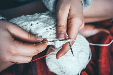 Girl knits lace socks on a plaid.