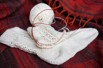 Knitted golf socks and knitting needles and a ball on a red plaid.