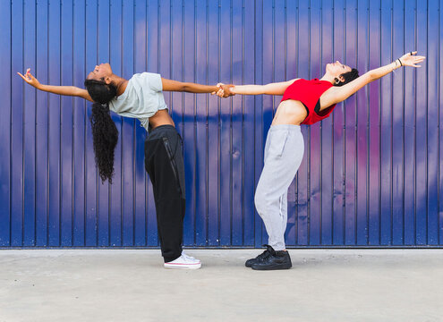 Multiethnic women dancing near blue wall