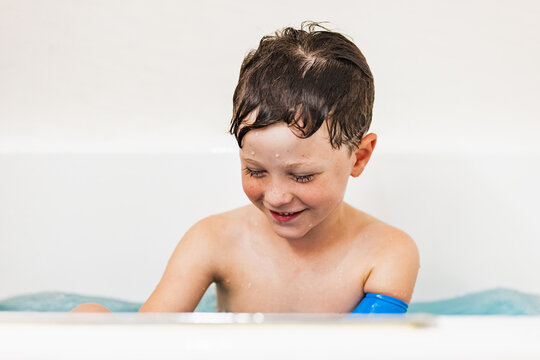 Boy wearing waterproof arm plaster protection in bathtub