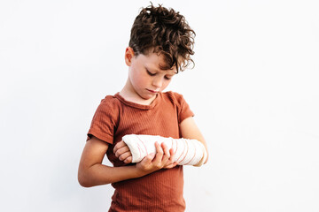 Unhappy boy with broken arm in plaster bandage
