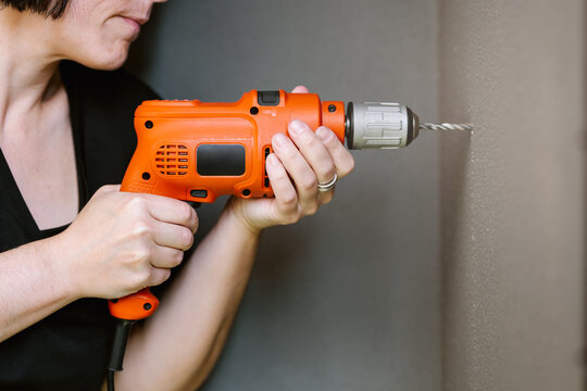 Anonymous woman drilling hole in wall