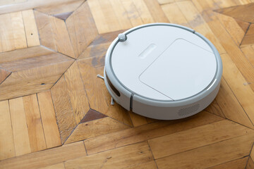Obraz na płótnie Canvas Robot vacuum cleaner stands on the light parquet floor, top view.