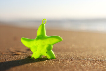 Sandy summer beach and plastic star fish at sunset
