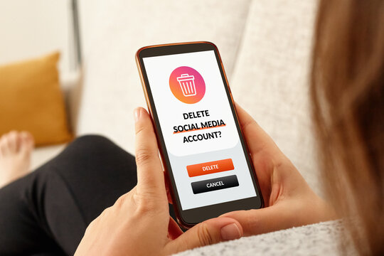 Close-up of girl on a sofa with smartphone deleting social media account.