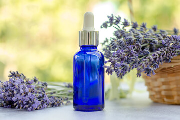 Obraz na płótnie Canvas Blue bottle with lavender essential oil on nature background