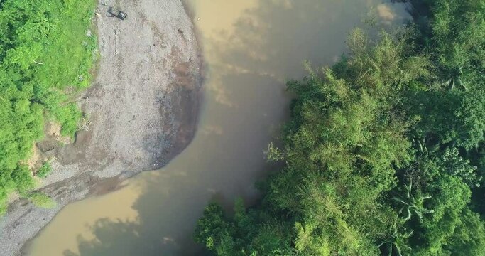 Big river with brown water surrounded by dense of trees. There are bamboo trees on the riverside. Central Java, Indonesia