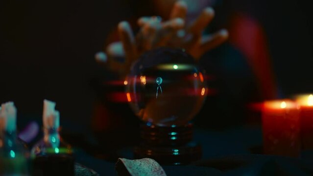 Mysterious woman witch whispering spells to crystal ball, forecasting future