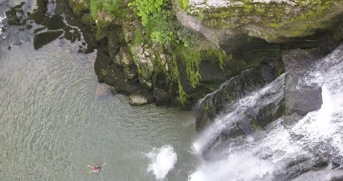 Young Cliff jumping athlete dives from a rock next to a waterfall in the Doubs river, Neuchatel, Switzerland. Fail