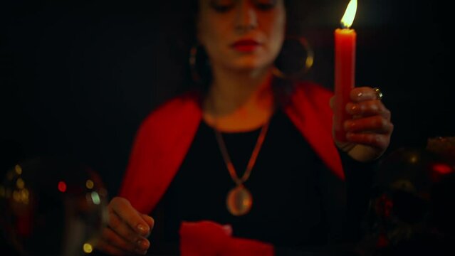 Concentrated woman psychic lighting candles, preparing to perform magic ritual