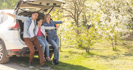 Family with kids sitting in car trunk