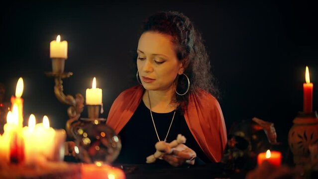 Female dark occultist practicing black magic, pinning voodoo doll, saying spell