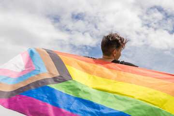Pride day 2022. Young lesbian girl holding the lgbtq+ flag on the pride day. Celebrating the lgbt lesbian, gay, bisexual, transgender, queer and other identities rights.