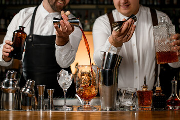 wonderful view on mixing cup with ice and shaker cups on the bar counter into which the bartenders...