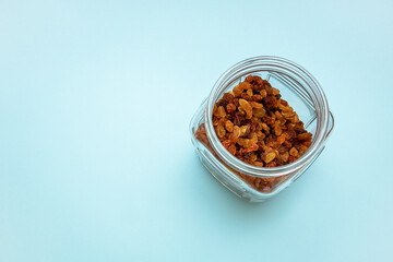 glass jar with raisins on a blue background top view from kopi space.