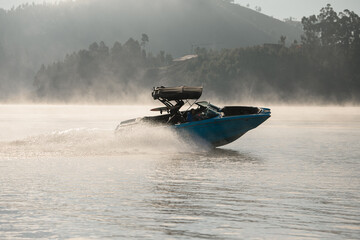 Fototapeta premium beautiful modern motorboat quickly floating on the water against the backdrop of trees and hill