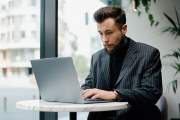 Fototapeta premium Young Caucasian business man working on laptop in cafe. Businessman, freelance