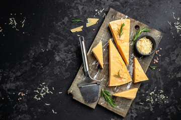 Parmesan cheese on a wooden board, Hard cheese, olives, rosemary and metal grater. place for text, top view
