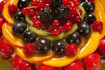 fruit tart with strawberries, blackberries, blueberries, peach slices and berries, detail seen from above