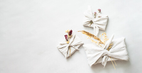 Presents wrapped in fabric and decorated dried flowers. Traditional Japanese gift wrapping furoshiki style. Zero waste holiday concept.