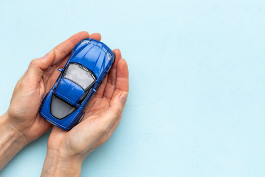 Toy car in hands, top view. Car insurance or driving safety concept