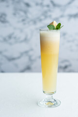 Yellow fresh seasonal summer long cocktail with banana smoothie on marble table for cafe or bar menu, refreshing concept