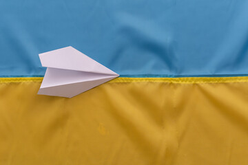 paper airplane on the background of the flag of Ukraine