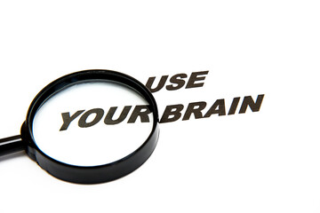 phrase use your brain on a white background next to a magnifying glass