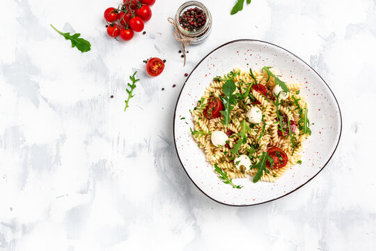 Caprese salad Pasta with tomato, mozzarella vegetable paste on a light background, vegetarian salad, banner, menu recipe place for text, top view
