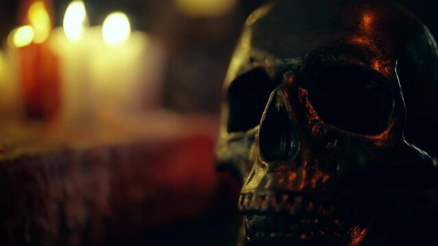 Spooky dark skull on table with burning candles, occult rites, black magic