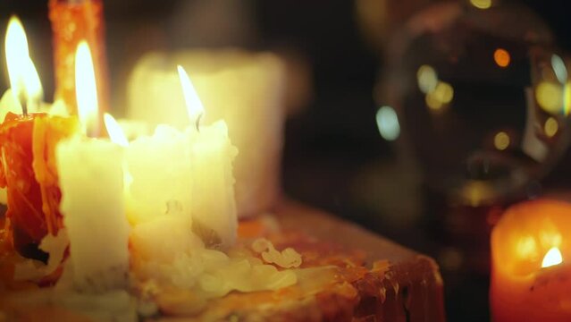 Burning candles, crystal ball and black skull standing on table, witchcraft room