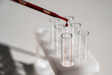 Close-up of a laboratory assistant dripping blood from a pipette into a test tube. 