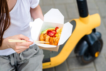 woman with scooter eating asian food