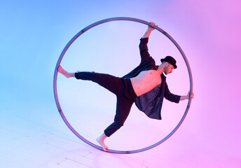 Fototapeta na wymiar Acrobat performing waltz trick with cyr wheel