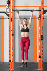 Fototapeta na wymiar Fit athletic woman doing a dead hang in a Crossfit gym