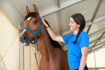 Young woman stroking the neck of her pet horse