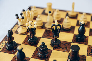 Antique handmade carved chess.Chess pieces on a high-quality chess board on a bright table in a...