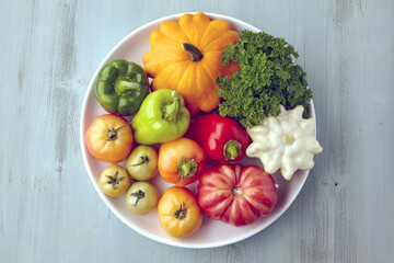 Ripe organic vegetables from the garden are laid out on a white plate