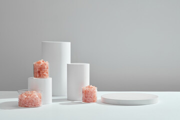 Front view of cosmetic jar decorated with white podium and himalaya salt white abstract background 
