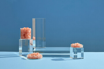 Front view of himalaya salt decorated with transparent podium in blue background abstract