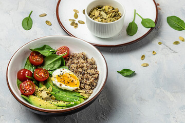 Keto diet plate quinoa, avocado, egg, tomatoes, spinach and sunflower seeds on light background. Healthy food, ketogenic diet, diet lunch concept, place for text, top view