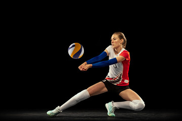 Dynamic portrait of professional volleyball player in sports uniform playing volleyball isolated on...