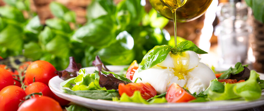 Salad with Tomatoes, Burrata, basil,olive oil. middle name Burratina. Traditional cheese from the south of Italy in the Puglia region. Round soft cheese inside liquid stracciatella texture. Banner